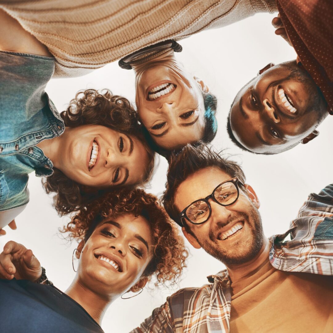 Fünf lachende Menschen unterschiedlicher Herkunft blicken gemeinsam in die Kamera