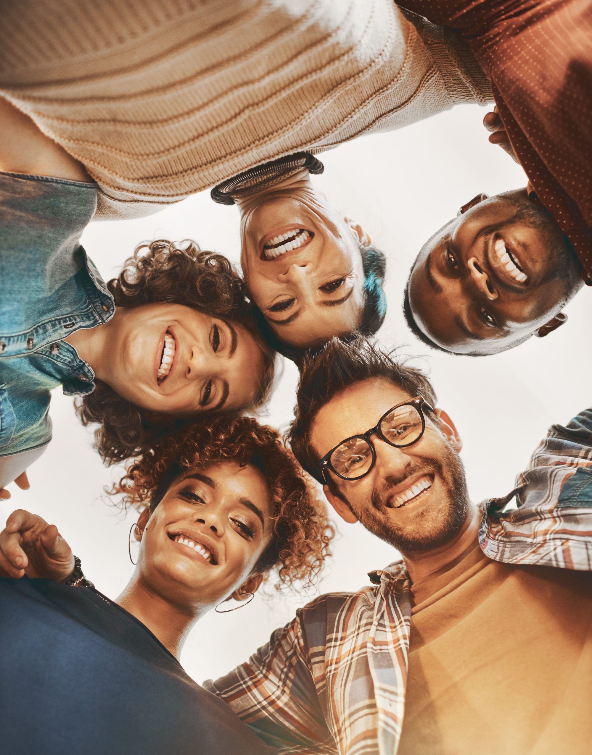 Fünf lachende Menschen unterschiedlicher Herkunft blicken gemeinsam in die Kamera