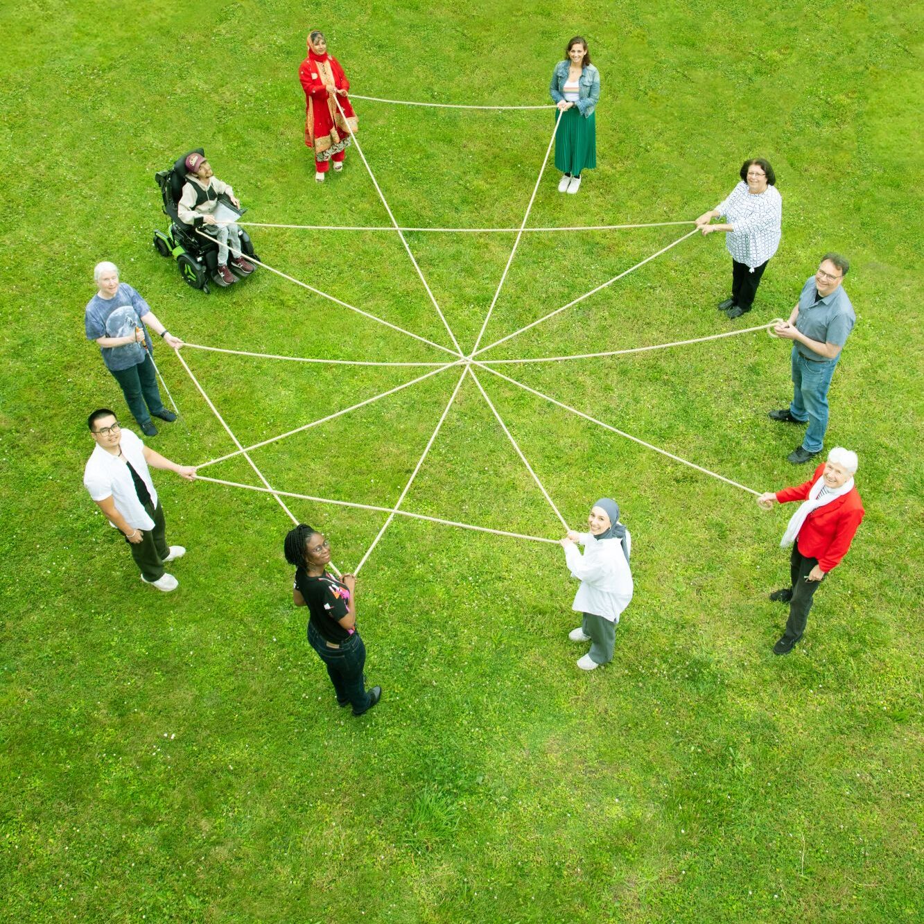Menschen halten gemeinsam Fäden zu einem Netz – Vogelperspektive