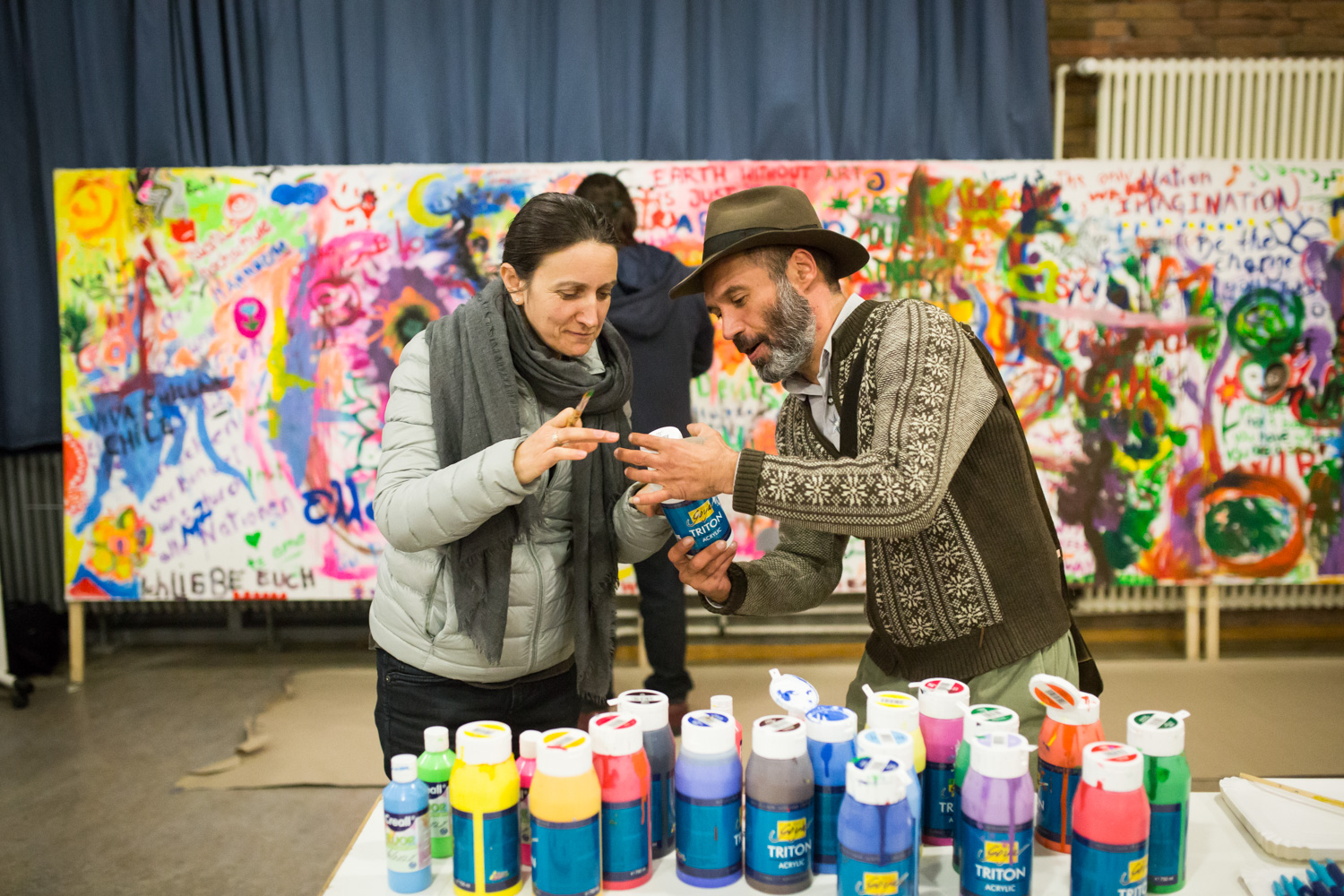 Zwei Personen vor einer bunten Gemeinschaftsmalerei