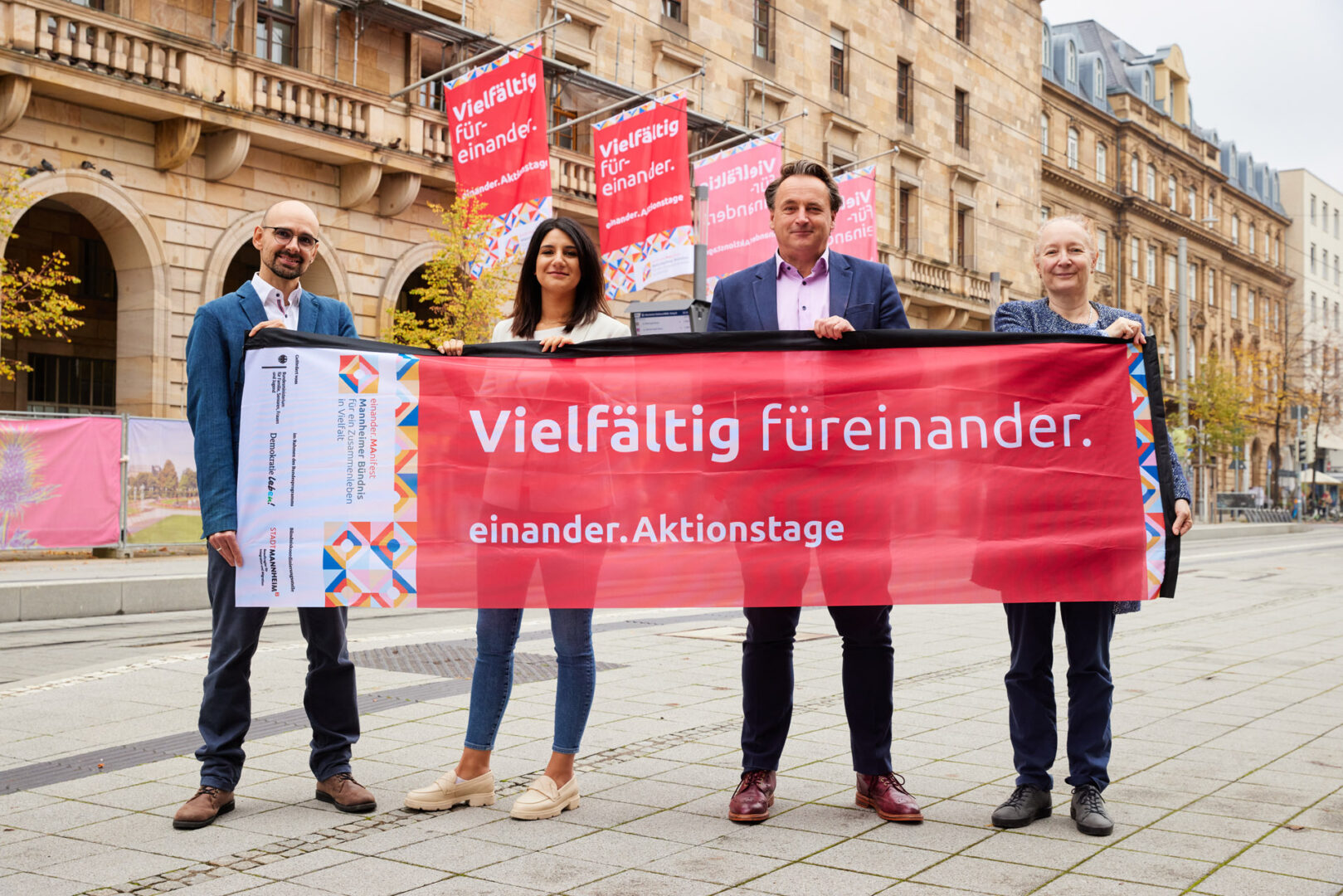 Andreas Schmitt, Aylin Salci, Claus Preissler, Sylvia Loeffler halten gemeinsam eine einander.Aktionstage Flagge